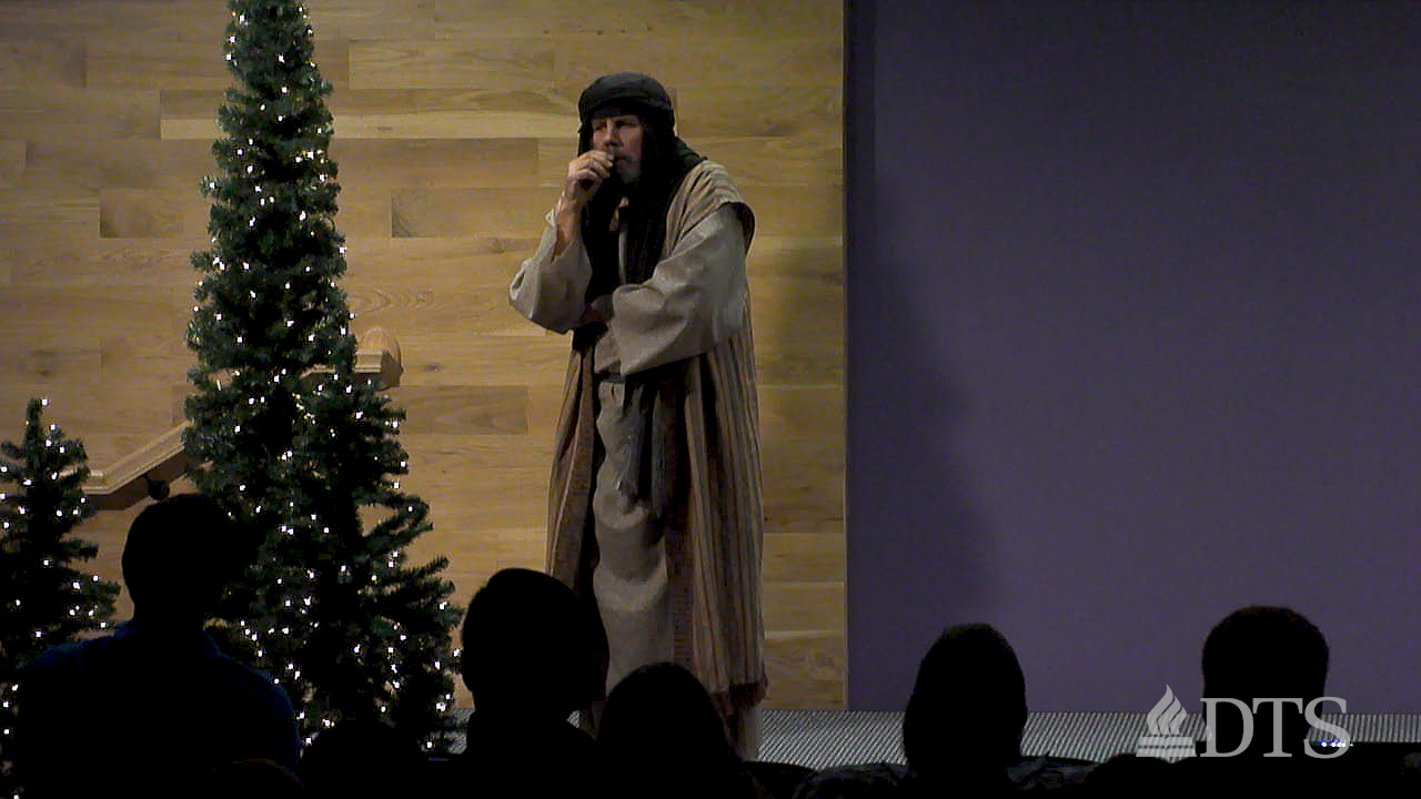 man dressed in costume standing near Christmas tree at DTS Chapel
