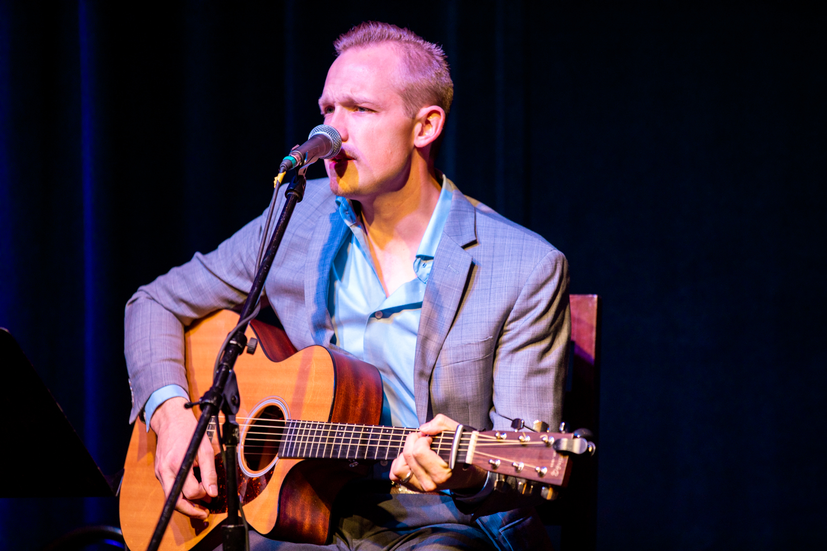 DTS alum Blain Larsen playing the guitar and singing into a microphone