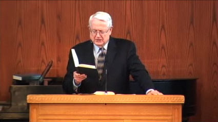 Dr. Chuck Swindoll standing at podium reading his Bible at DTS Chapel