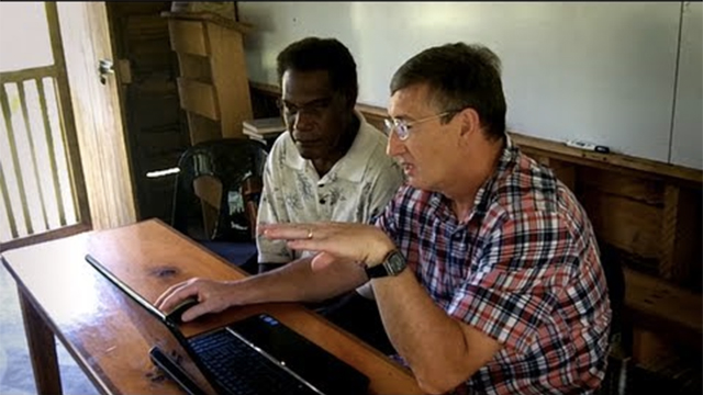 Dr. Ed Condra talking with a man while using a computer