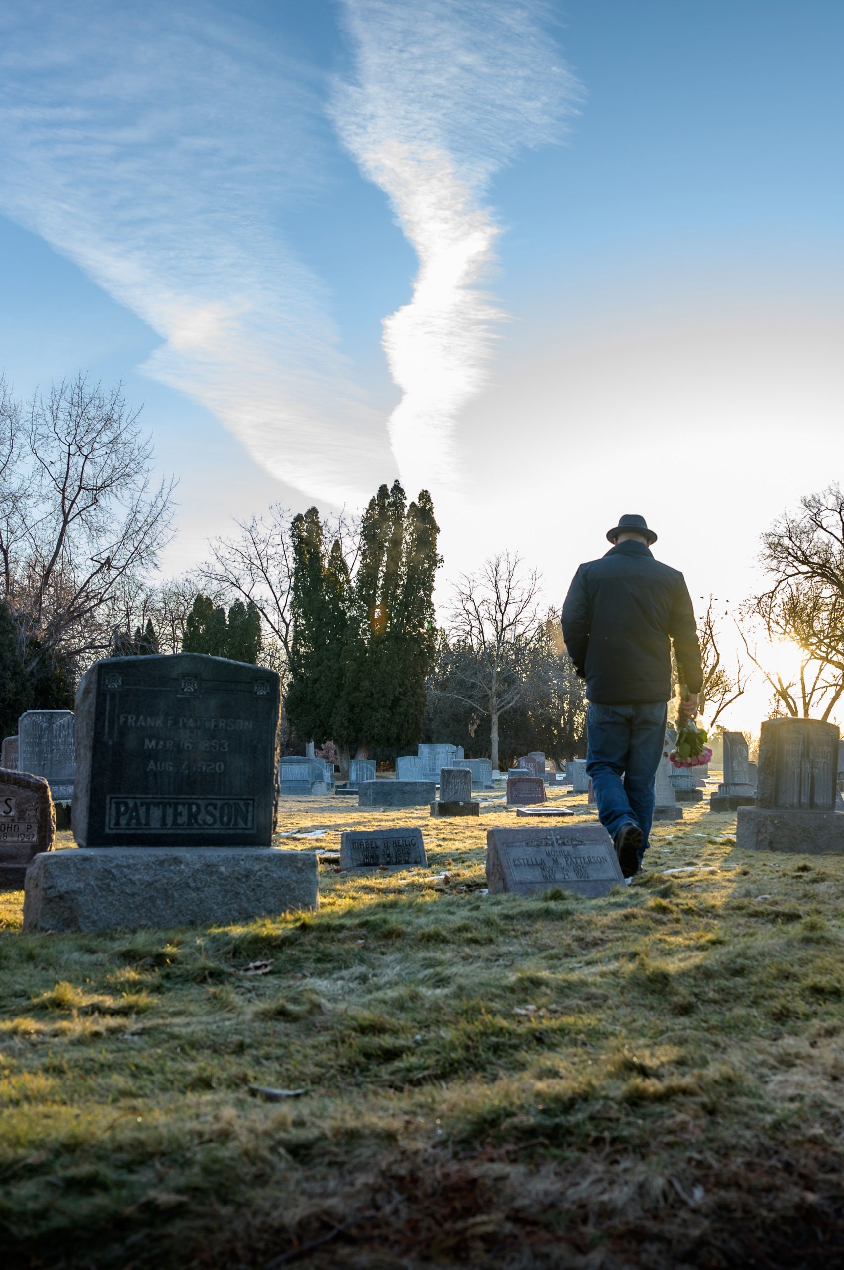 Lone figure of a man walking through a cemetery.